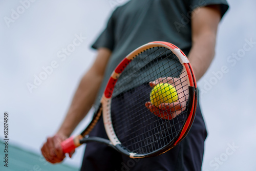 young coach or player holding tennis racket and ball while playing on court close-up © Guys Who Shoot