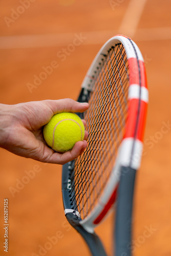 young coach or player holding tennis racket and ball while playing on court close-up