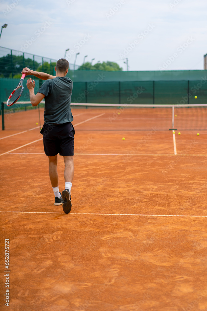 Obraz premium young professional player coach on outdoor tennis court practices strokes with racket and tennis ball