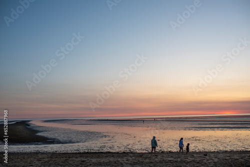 A family plays around on low tide during a Cape cod summer sunset