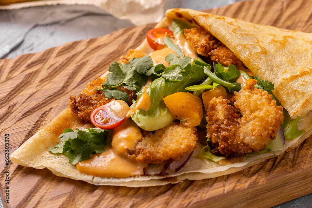 Pancake or crepe with fried shrimp tomatoes and vegetables and cheese close-up top view