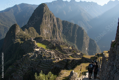 Panorama of Machupicchu with view of the mountains and archeological site, along with a stone staircase to the ruins with silhouettes of people descending it, in Peru, Sacred Valley. 