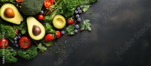 Minimalistic arrangement of vegetarian food ingredients with natural elements Raw food idea featuring avocado kale and tomatoes Organic produce on concrete backdrop room to add text Clean nu