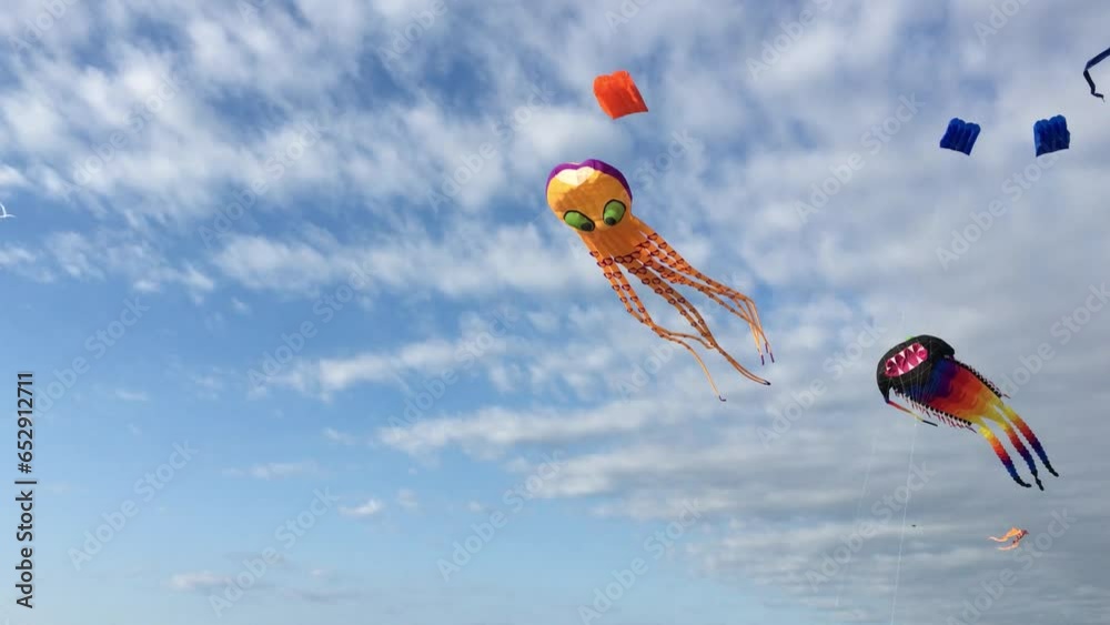 Flying kites against blue sky and clouds background at sunset on sunny day in summer. City kite festival. Two kites flutters in the wind.
