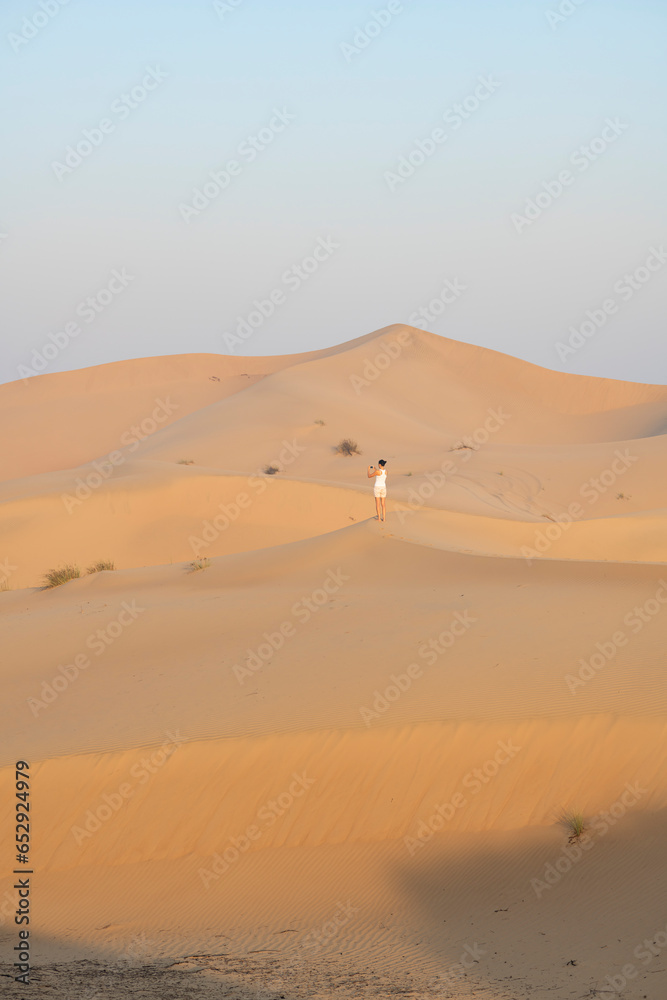 Woman taking a pictures of dunes in the desert with copy space, travel concept, desert landscape