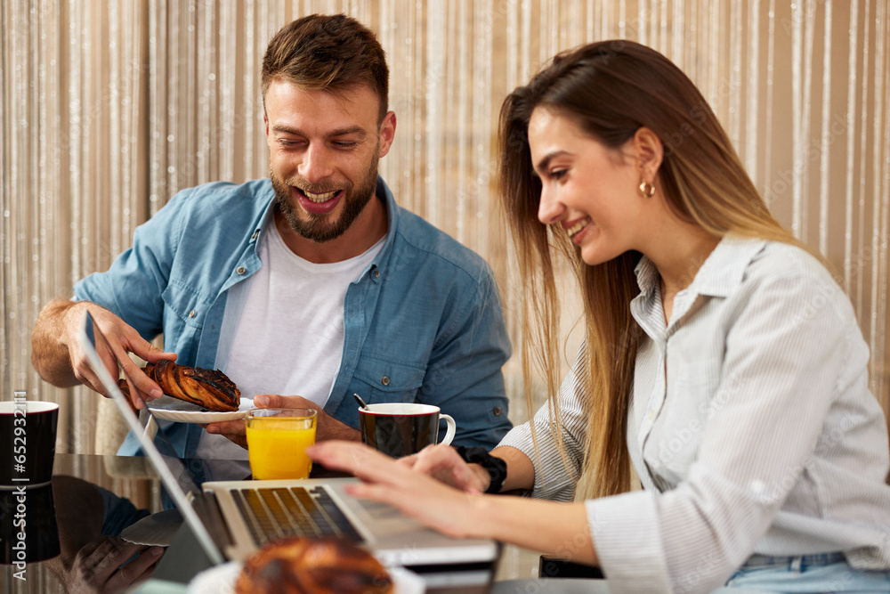 Young couple is having breakfast and using a laptop Young couple is having breakfast and using a laptop