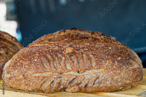 freshley baked loaf of artisanal bread with selective focus on the decorative scoring in the crust on the side of the loaf