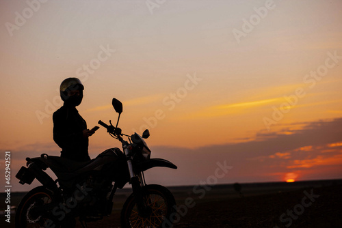 silhouette of a motorcyclist at sunset with an enduro motorcycle  the concept of the romance of motorcycle life.