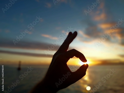 Une main qui attrape le soleil au sunset