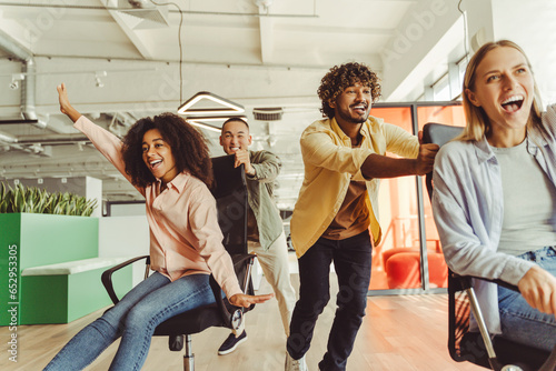 Multi ethnic colleagues having fun racing on chairs at the office photo