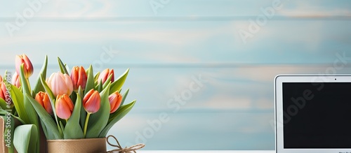 Laptop and tulip flowers on blue background Spring holidays online shopping concept Top view #652963984