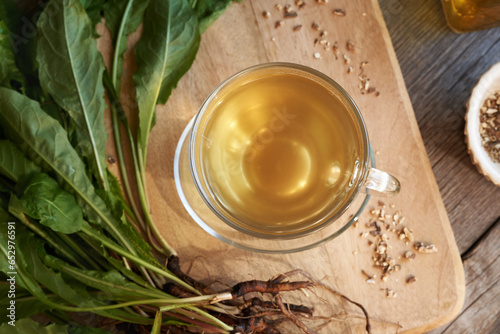 A cup of dandelion tea with fresh roots and leaves