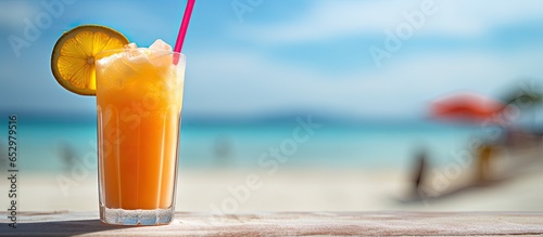 Tropical beverage on sandy beach with blurry beach behind photo