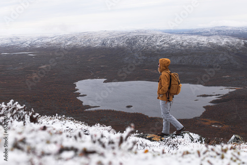 Young woman with a backpack standing on top of a mountain Saana, Finland, Lapland photo