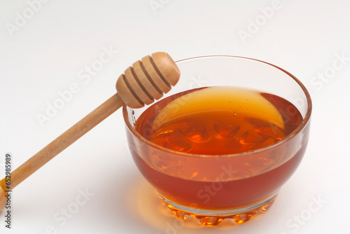 Honey dripping from spoon in the cup in golden sunlight