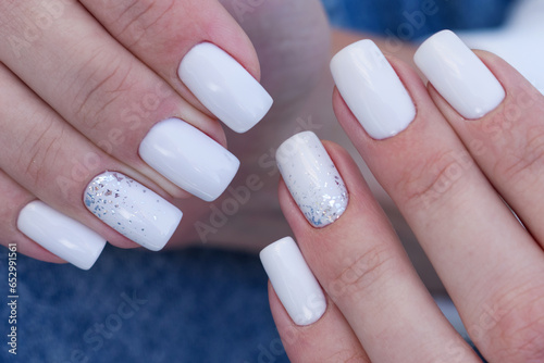 nails with elegant white manicure, hands close-up on blue background