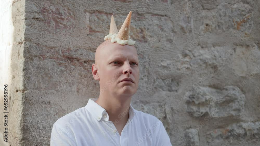 Bald man with ice cream cones on his head , an ice cream mohawk