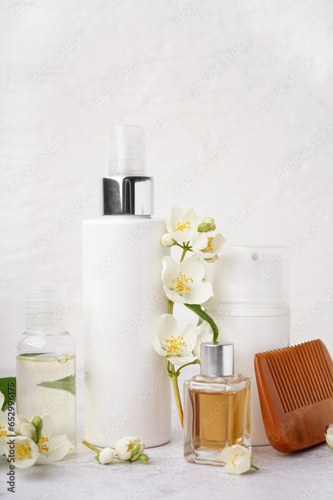 Set of cosmetic products, hair comb and beautiful jasmine flowers on light background