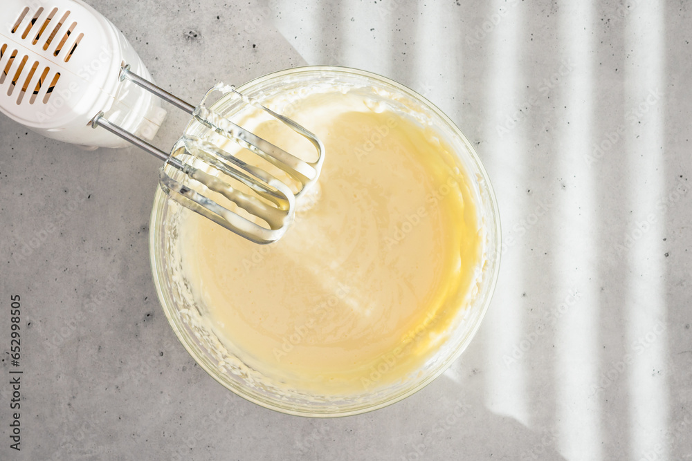 Cheesecake batter in a glass bowl. Cheesecake recipe, preparation process. Mixing batter in a glass bowl, flat lay - obrazy, fototapety, plakaty 
