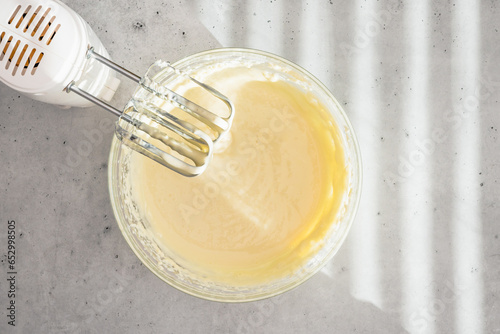 Cheesecake batter in a glass bowl. Cheesecake recipe, preparation process. Mixing batter in a glass bowl, flat lay