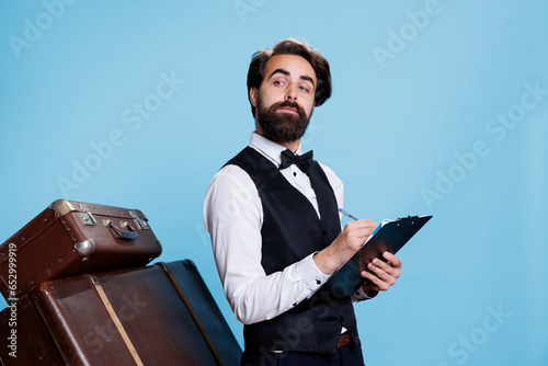 Obraz na plátně Classy bellhop creating guestlist at hotel, using archive record files on clipboard to keep evidence