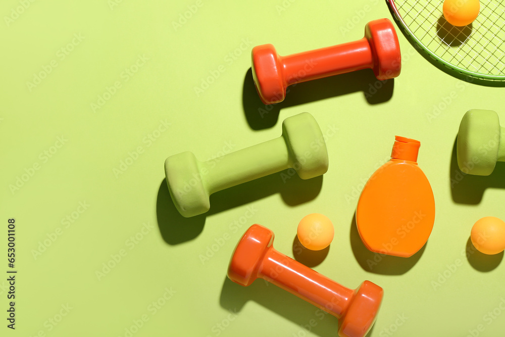 Composition with bottle of sunscreen cream, dumbbells and ping pong balls on color background Composition with bottle of sunscreen cream, dumbbells and ping pong balls on color background