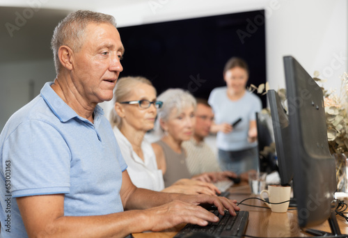 Concerned old man sitting at computer while trainer speaking on the background