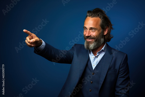 middle age man wearing formal clothes pointing to the side with finger and hand looking at the side in front a blue background