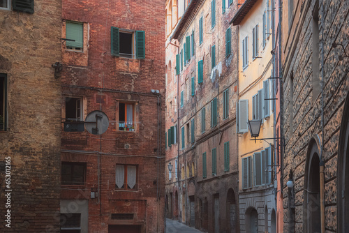 Colourful residential buildings along a quaint and narrow backstreet in the historic Tuscan old town of Siena, Tuscany, Italy.