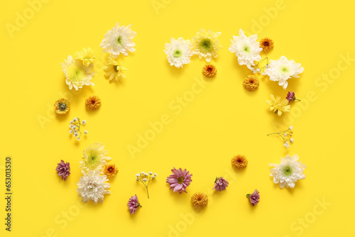 Frame made of beautiful chrysanthemum flowers on yellow background