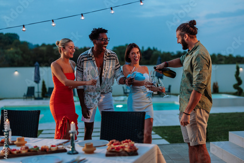 Photography Guy is pouring his fiends wine at a pool dinner party