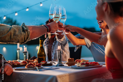 Bild auf Leinwand Friends raising glass to do a toast during poolside dinner