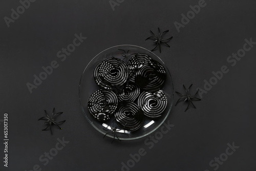 Halloween composition with spiders and licorice candies on black background photo