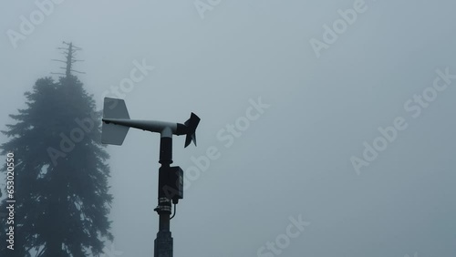 Metal weather vane with propeller spins in mountains in wind. Video 4k resolution. Cloudy and rainy weather in mountains. Deteriorating weather and poor visibility. Thick fog in mountains. photo