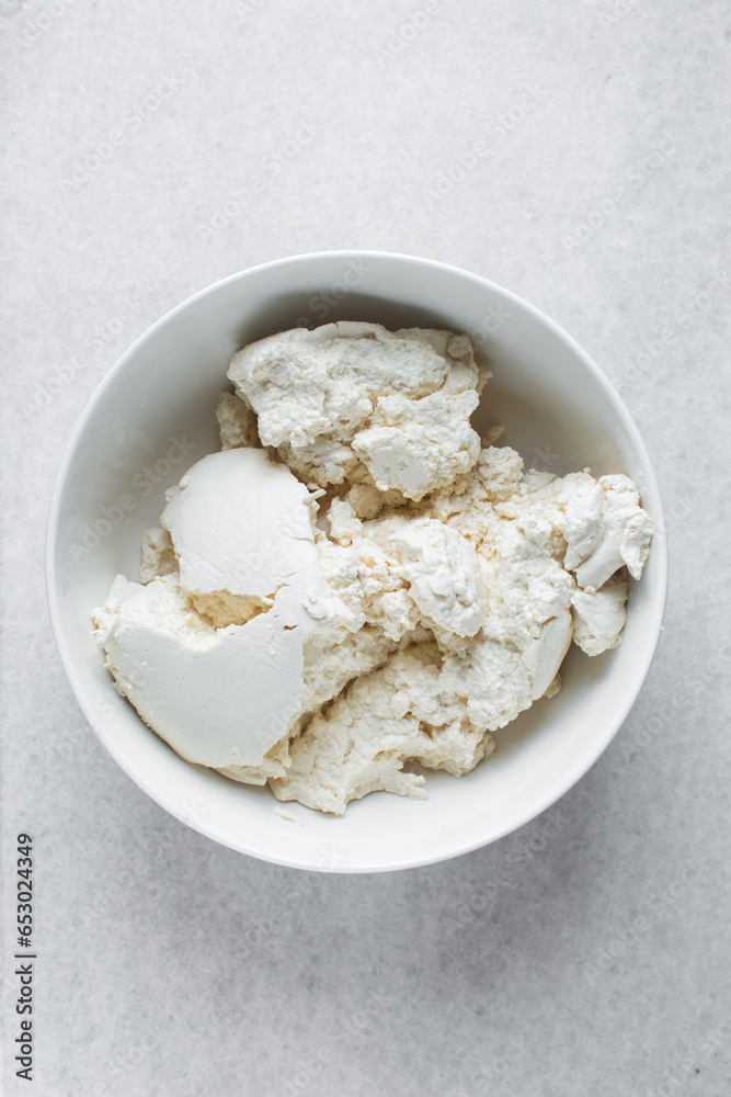 Strained Greek yogurt in a white ceramic bowl, process of making Greek yogurt, strained thick yogurt in white mixing bowl Strained Greek yogurt in a white ceramic bowl, process of making Greek yogurt, strained thick yogurt in white mixing bowl