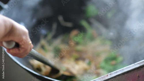 Street food vendor preparing fried flat rice noodle also known as kway teow (kwetiau). Popular Penang street, indonesian woman preparing noodles, famously known as Char Koay Teow. photo