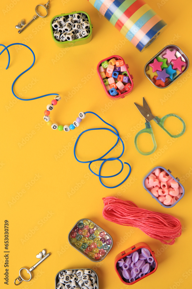 Handmade jewelry kit for kids. Colorful beads, bracelet and different supplies on orange background, flat lay