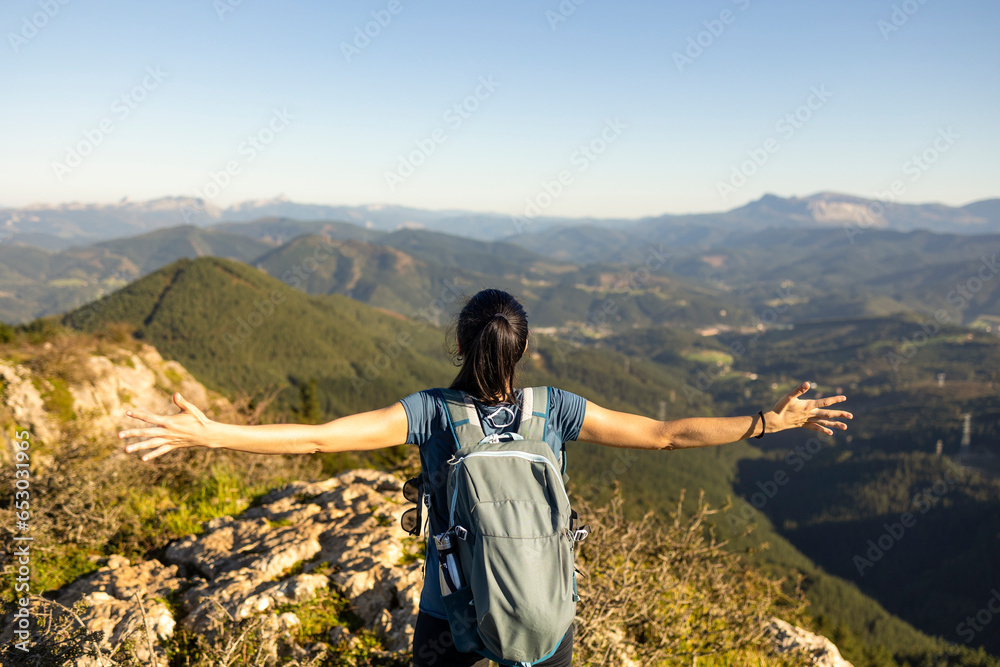 A young woman opens her arms, marveling at the natural mountain scenery in the Basque Country