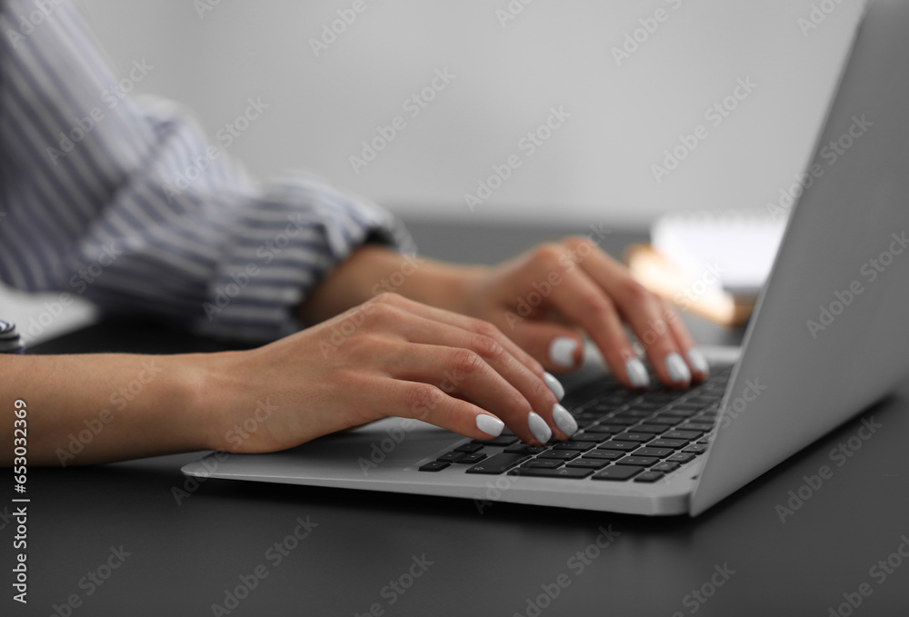 Woman using modern laptop at black desk, closeup Woman using modern laptop at black desk, closeup