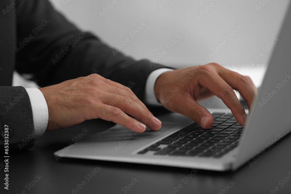 Man using modern laptop at black desk, closeup Man using modern laptop at black desk, closeup