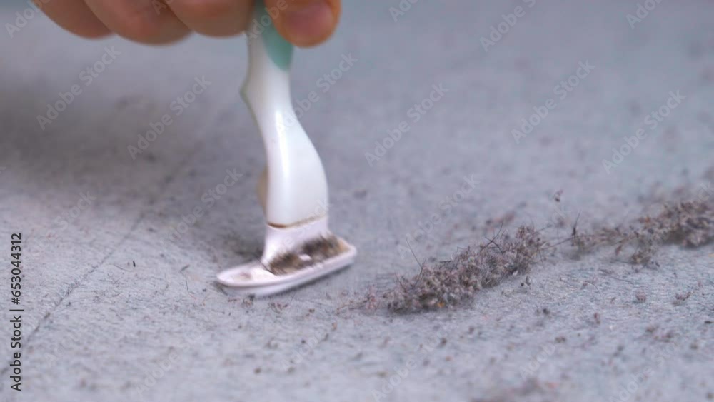 Fingers hold blade, cut pellets from old sofa, clean the surface couch