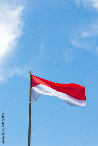 Indonesia's red and white flag fluttering under the blue sky tied to a bamboo stick