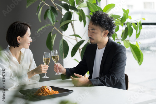Man and woman staring at each other eating in a restaurant, holding wine glasses, date or couple
