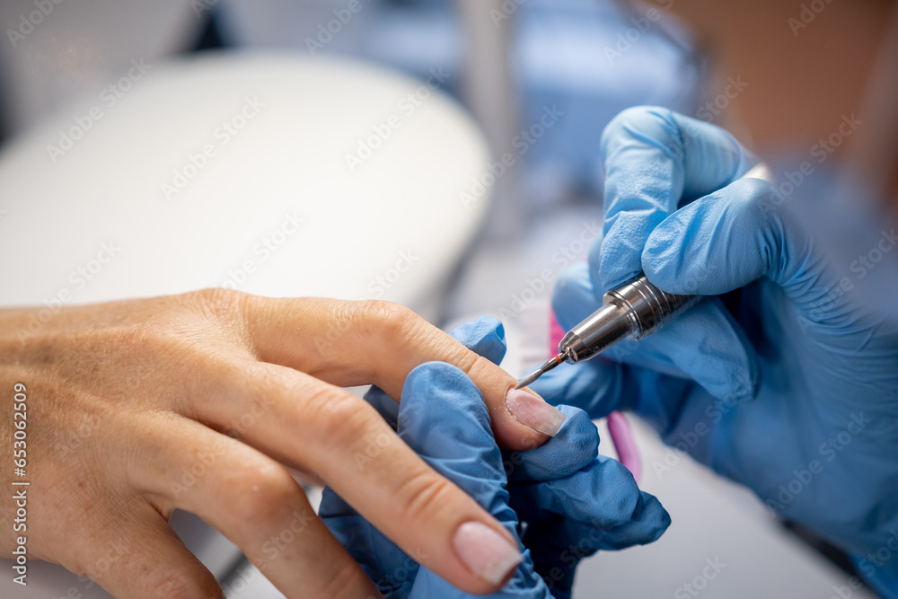Nail care procedure in a beauty salon. Female hands and tools for manicure, process of performing manicure in beauty salon. Concept spa body care. Gloved hands of a skilled manicurist cutting cuticles Nail care procedure in a beauty salon. Female hands and tools for manicure, process of performing manicure in beauty salon. Concept spa body care. Gloved hands of a skilled manicurist cutting cuticles