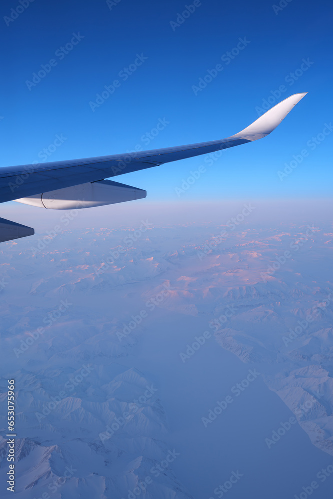 An airplane wing and a view on a North Pole snowy landscape while flying the polar route. An airplane wing and a view on a North Pole snowy landscape while flying the polar route.