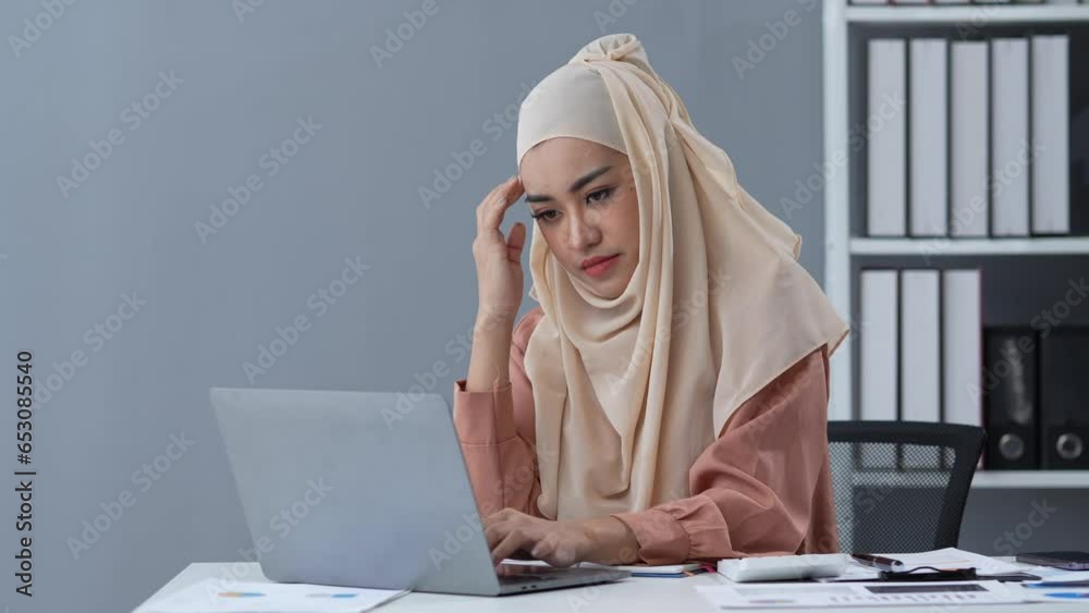 Islamic businesswoman who is tired, sleepy, bored from sitting at a desk for a long time and has office syndrome Islamic businesswoman who is tired, sleepy, bored from sitting at a desk for a long time and has office syndrome