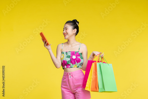 young woman holding shopping bags and smart phone