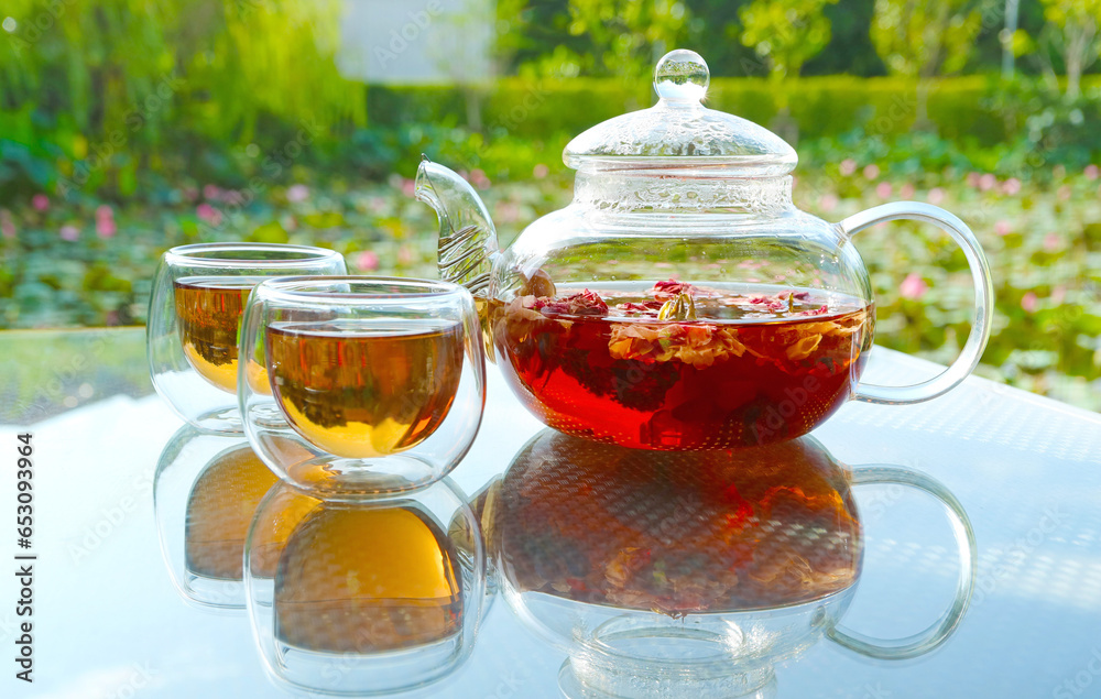 Cups of hot fragrant rose tea being served on garden table Cups of hot fragrant rose tea being served on garden table
