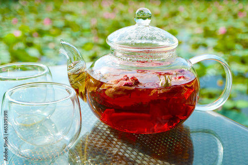 Closeup of rose tea being steeped in a teapot on garden table