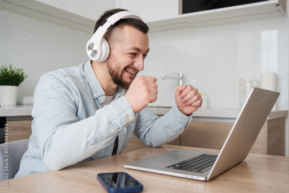Young man with laptop and headphones indoors at home, studying, freelance working Young man with laptop and headphones indoors at home, studying, freelance working